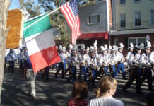 Parade Fundraiser: Comedy Night at the Harbor this Thursday Parade marchers in uniform with plumed hats marching down a street, carrying Italian and American flags as spectators watch from the curb.
