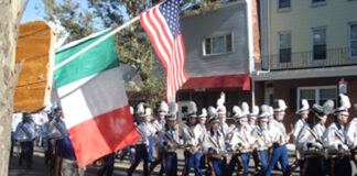 Parade Fundraiser: Comedy Night at the Harbor this Thursday Parade marchers in uniform with plumed hats marching down a street, carrying Italian and American flags as spectators watch from the curb.