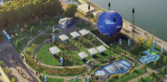 A big soccer ball is coming to East Boston’s waterfront Aerial view of a waterfront festival with white tents, a circular lawn, a large blue inflatable stage, seating areas, and a water feature.