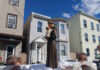 Sacred Heart marks the feast of St. Anthony with annual procession Statue of a saint holding the baby Jesus on a float, carried during a street parade, with row houses in the background.