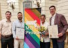 Senator Edwards and Representative Madaro celebrate Inaugural Commonwealth Pride Awardees Four people pose with a bright MA Proud banner; two hold official certificates and one carries a bouquet of sunflowers.