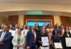 Latinos for Education Honors Brooke Charter School Multilingual Learner Coordinator Lesley Peรฑa Group of diverse professionals posing with certificates at an awards or graduation event in a conference room.