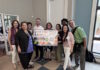 Maverick Landing Community Services launches Grab & Go produce market, expanding affordable fresh food access across East Boston Nine diverse adults stand indoors, smiling and holding a colorful 'Grab & Go Launch' banner for a community food program.