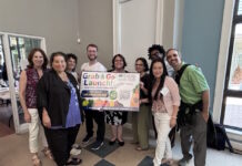 Maverick Landing Community Services launches Grab & Go produce market, expanding affordable fresh food access across East Boston Nine diverse adults stand indoors, smiling and holding a colorful 'Grab & Go Launch' banner for a community food program.
