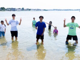 Two hundred fifty kids Boston kids had a blast at Save the Harborโs Annual Eastie Beach Bash Group of kids standing in knee-deep water at the beach, posing and making peace signs.