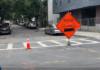 Residents and businesses are fed up with the parking situation in East Boston Orange 'Road Closed' sign with a black left arrow and a traffic cone on a city street near a crosswalk, indicating road construction.